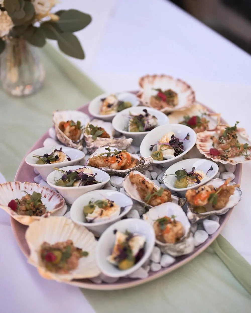Platte mit Fingerfood auf Jakobsmuscheln und Austernschalen